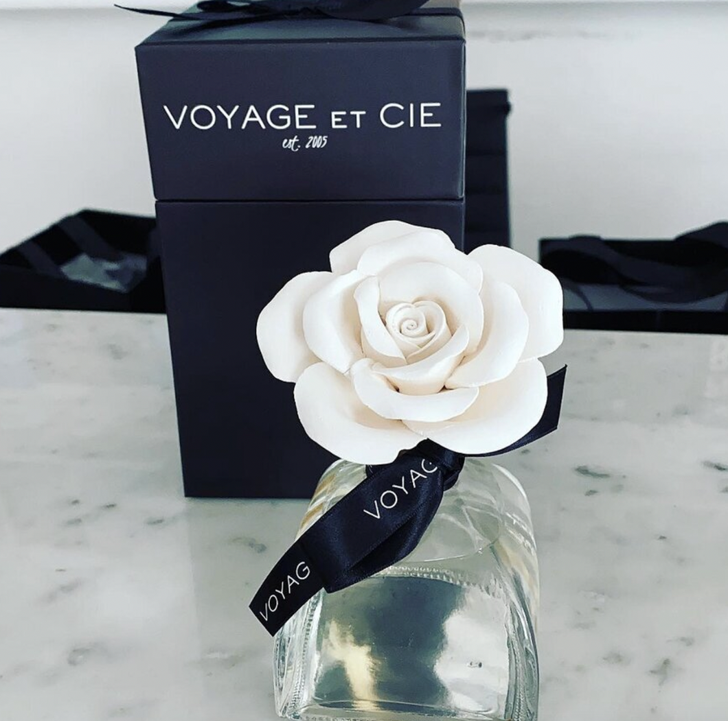 White porcelain rose diffuser in a clear glass oil container with navy ribbon bow.